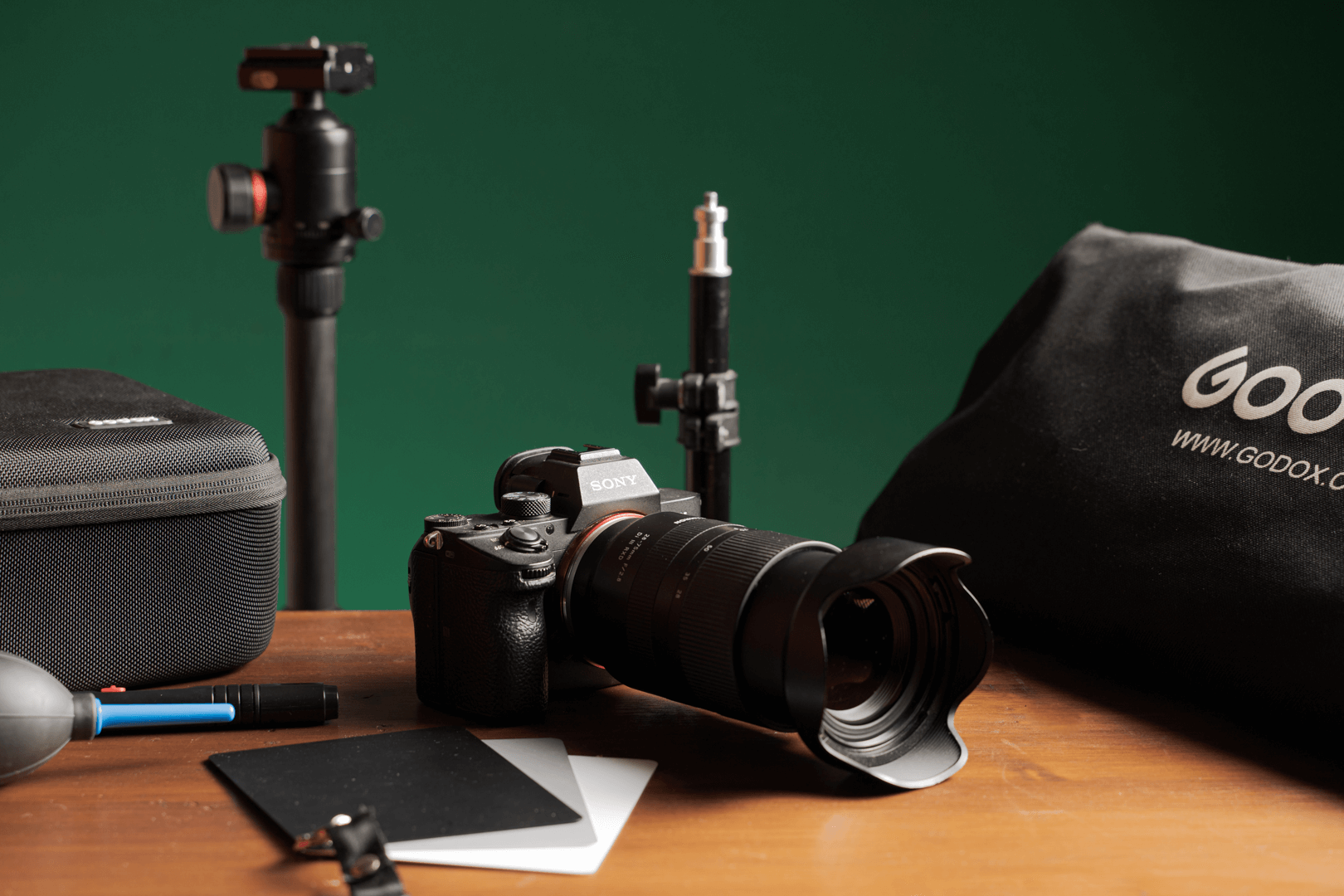 Cámara con objetivo, trípode y material de iluminación sobre una mesa de estudio