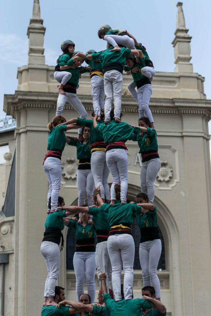 Castell humano de castellers con camisa verde frente a un edificio histórico