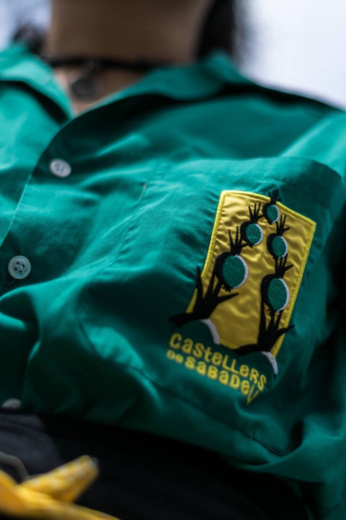 Detalle de la camisa verde y el escudo de un casteller