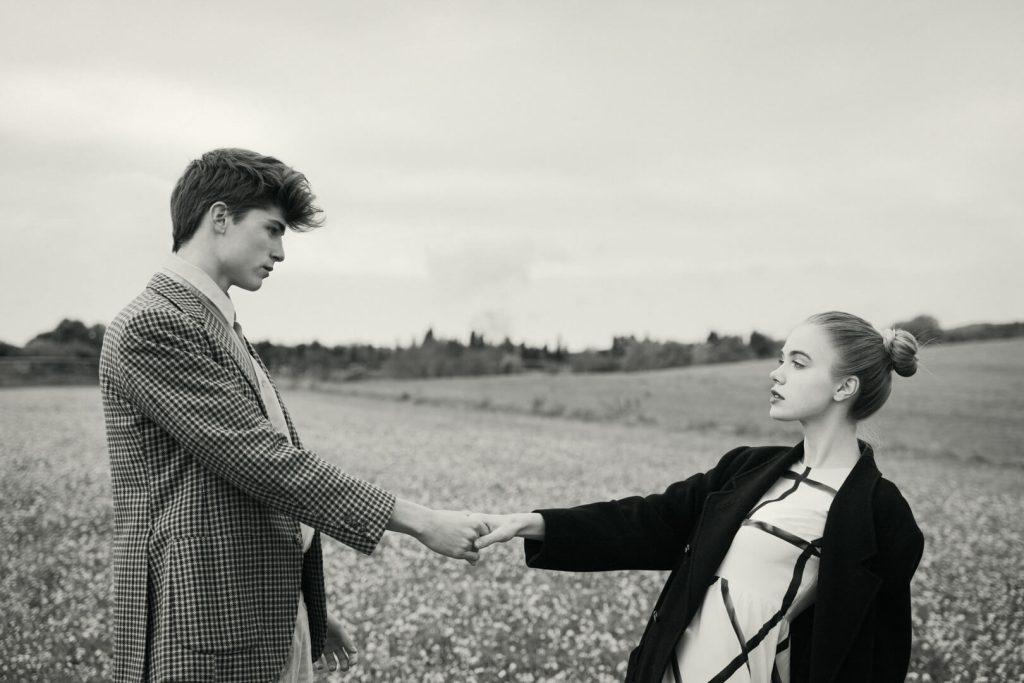 Editorial en blanco y negro de una pareja dándose la mano en un campo