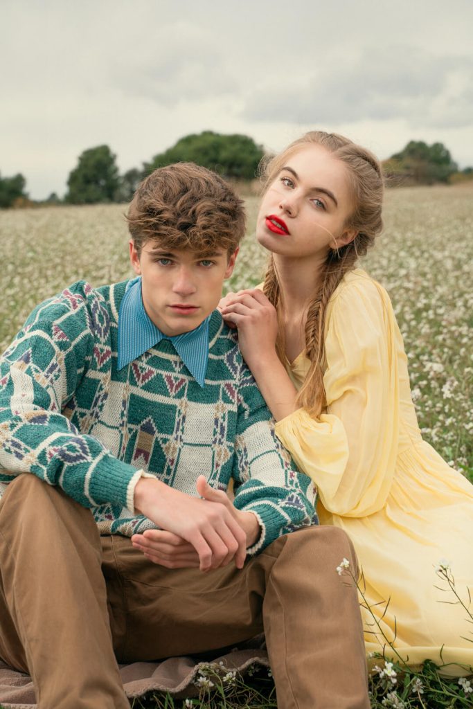 Editorial de moda con una pareja sentada en un campo de flores