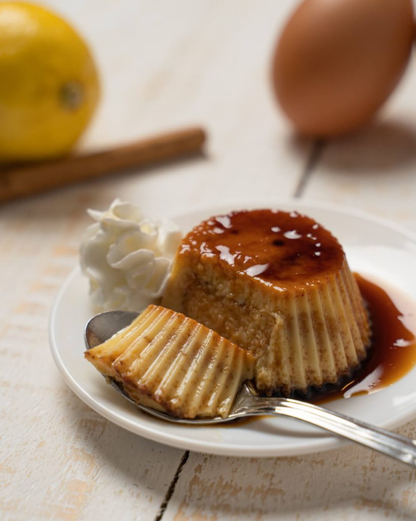Flan cortado con caramelo y nata en un plato blanco