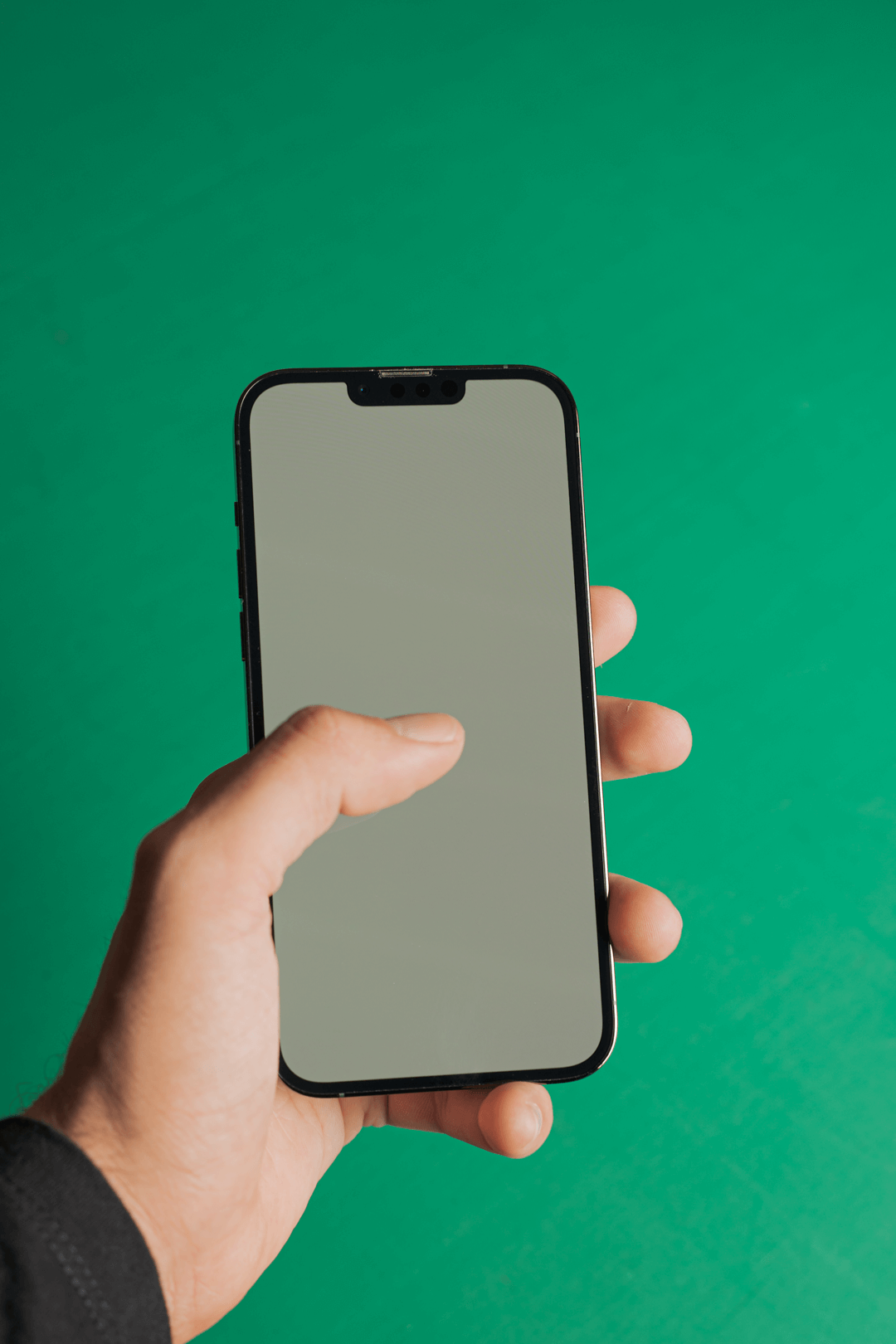 Mano sosteniendo un teléfono móvil sobre fondo verde, gestión de redes sociales