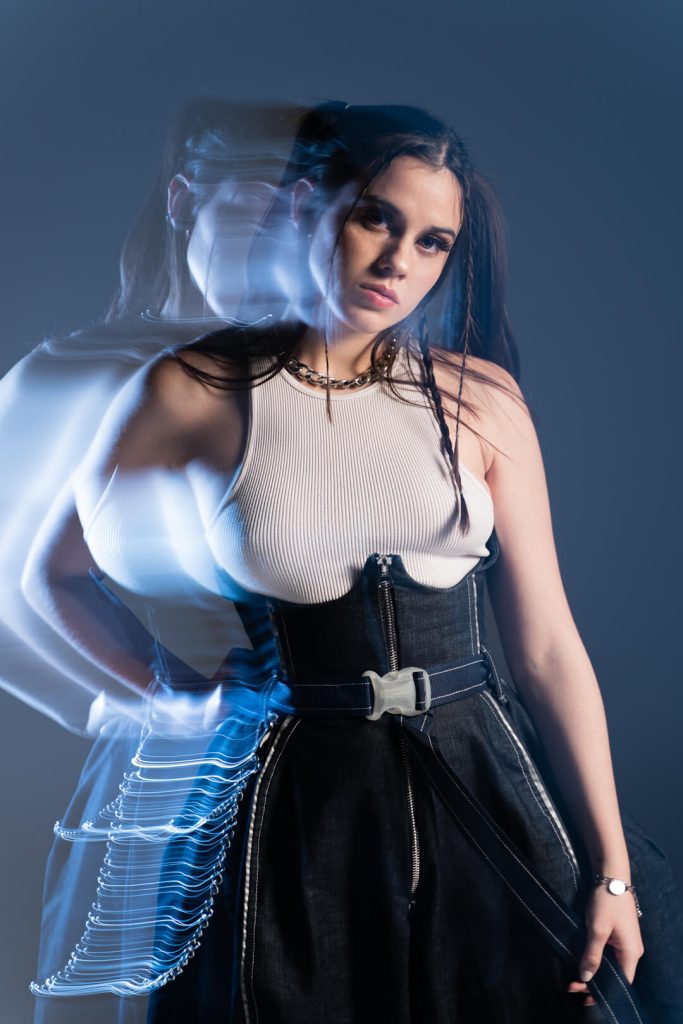 Fotografía de moda en estudio con vestido negro y estelas de luz azul de larga exposición