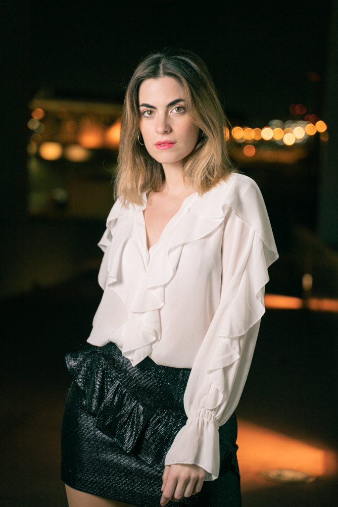 Mujer con blusa blanca de noche con luces desenfocadas de fondo