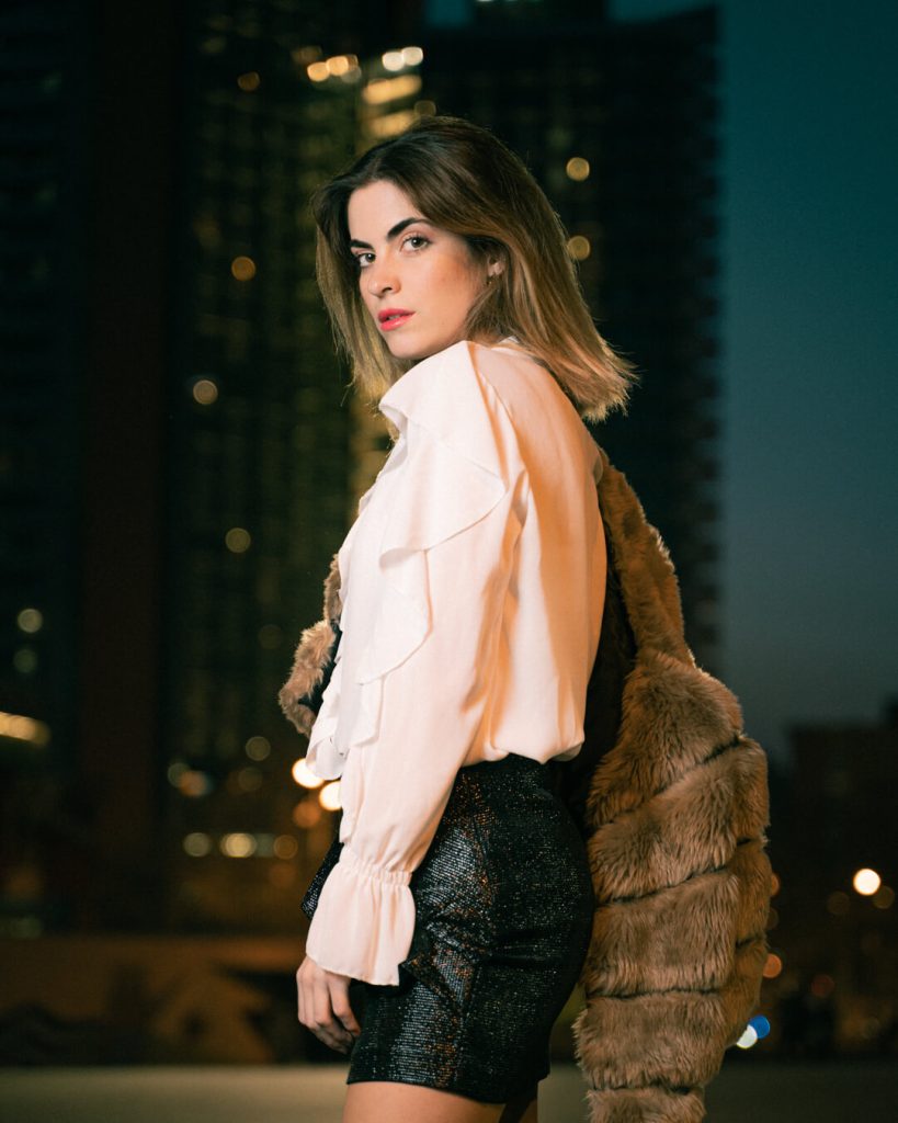 Fotografía de moda nocturna: mujer con blusa rosa y falda de cuero en la ciudad