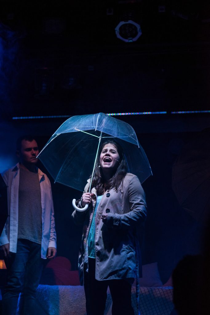 Actriz con un paraguas transparente en escena, fotografía de teatro