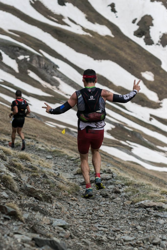 Corredor de trail subiendo una ladera con restos de nieve