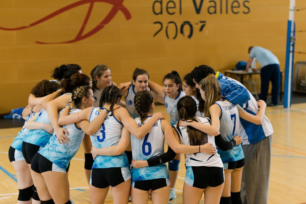 Equipo de voleibol haciendo piña en el centro de la pista